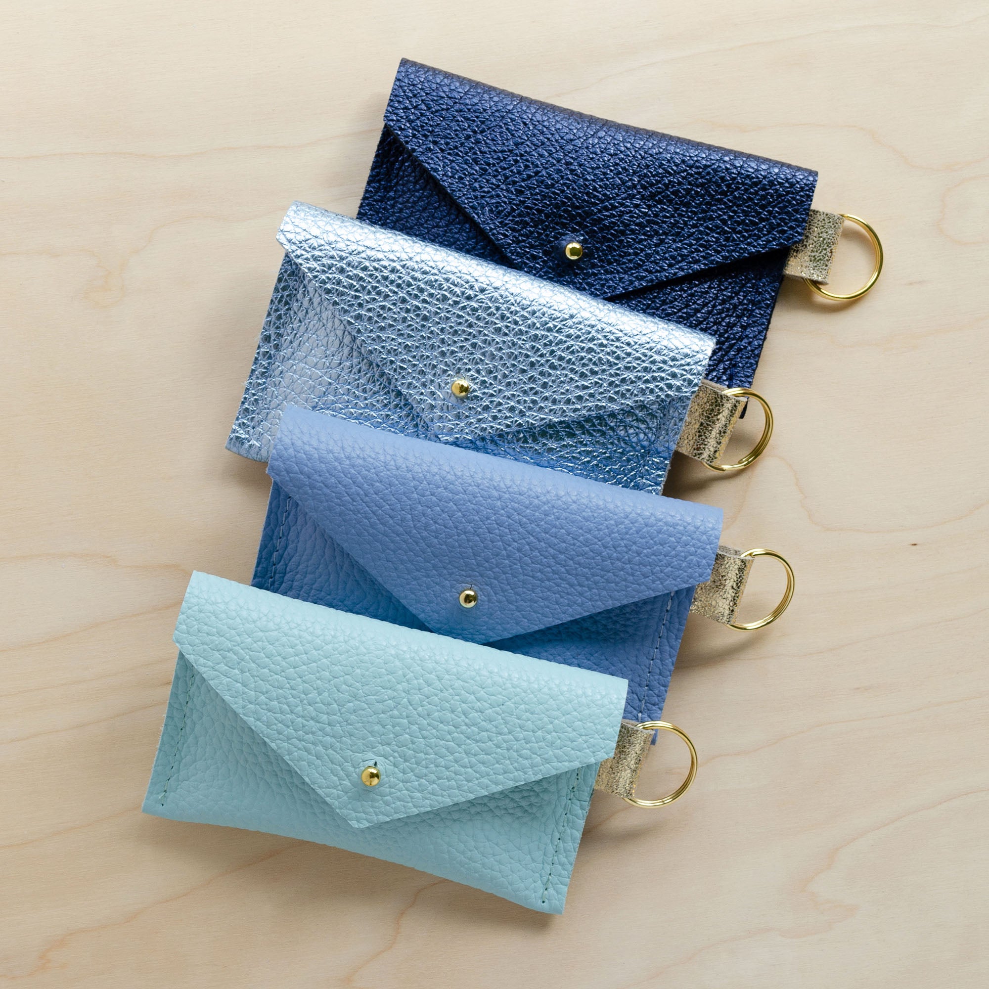 Four of the leather keyring card holders in Metallic Navy, Metallic Diamond, Powder Blue and Seaglass.