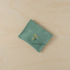 Mint green suede jewellery pouch with personalisation in gold. It holds the initials KM above the gold fastening.