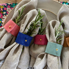 5 of the suede napkin rings displayed with linen napkins and tableware.