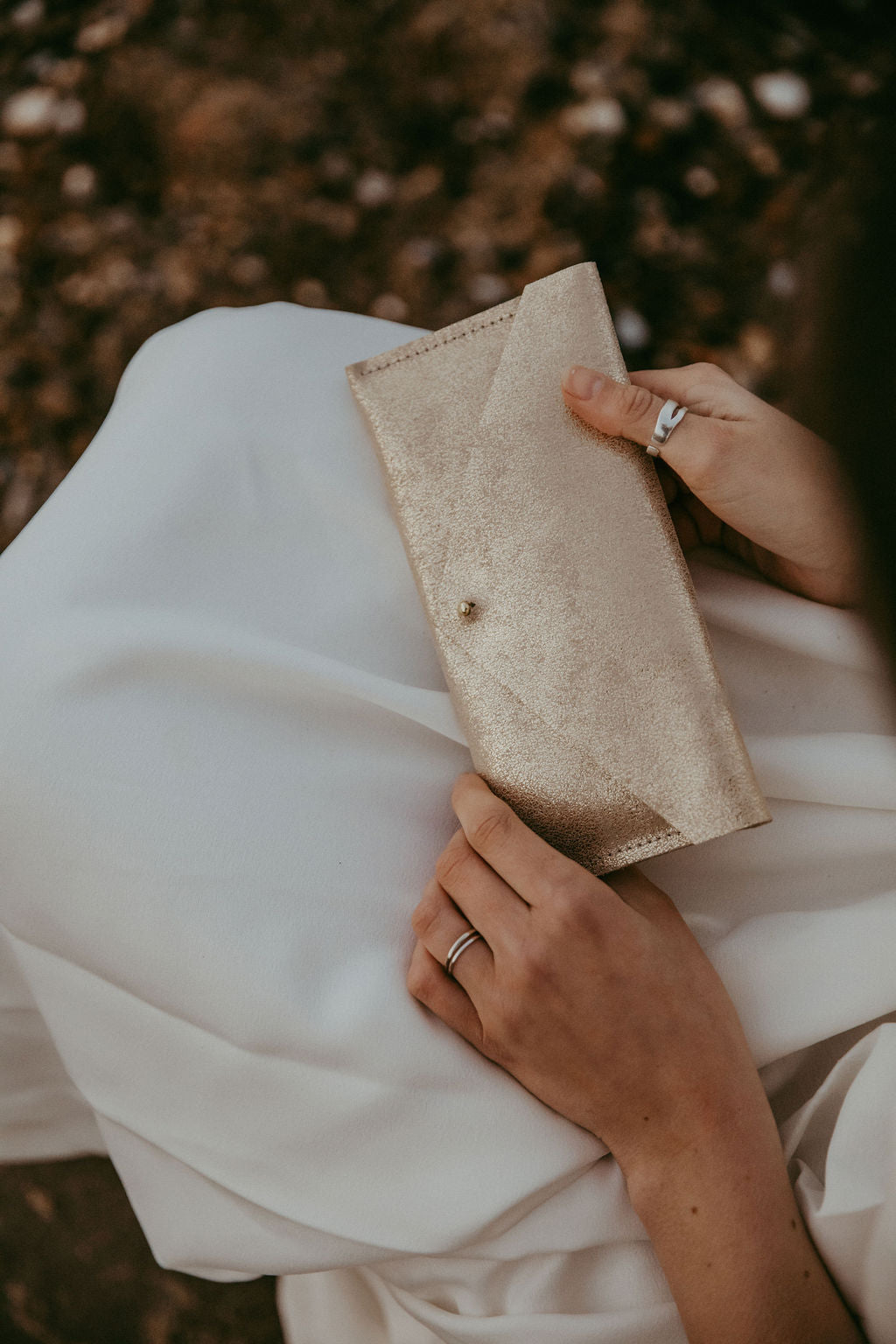 Gold leather clutch bag held by bride.