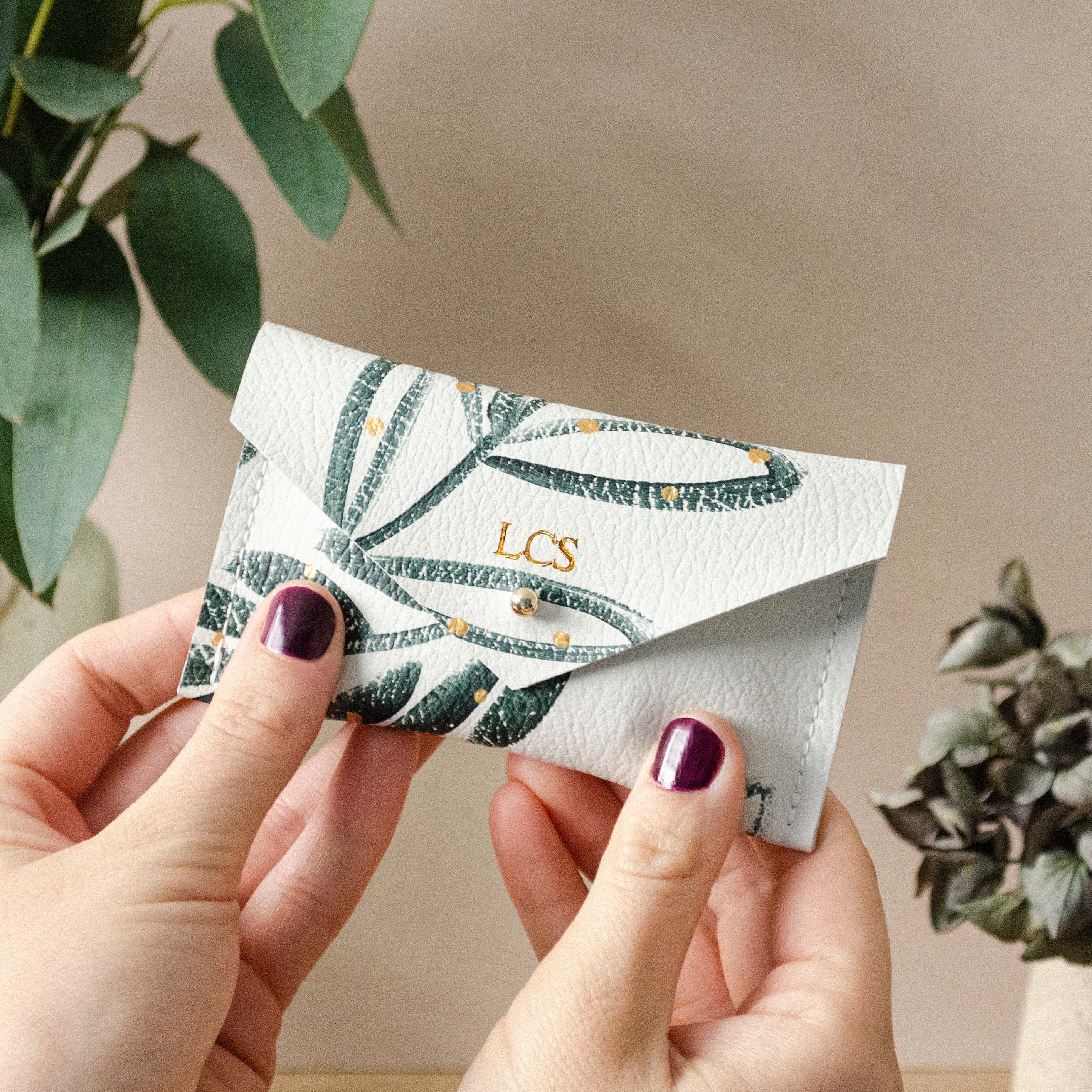 Botanical leather card holder with initials on it.