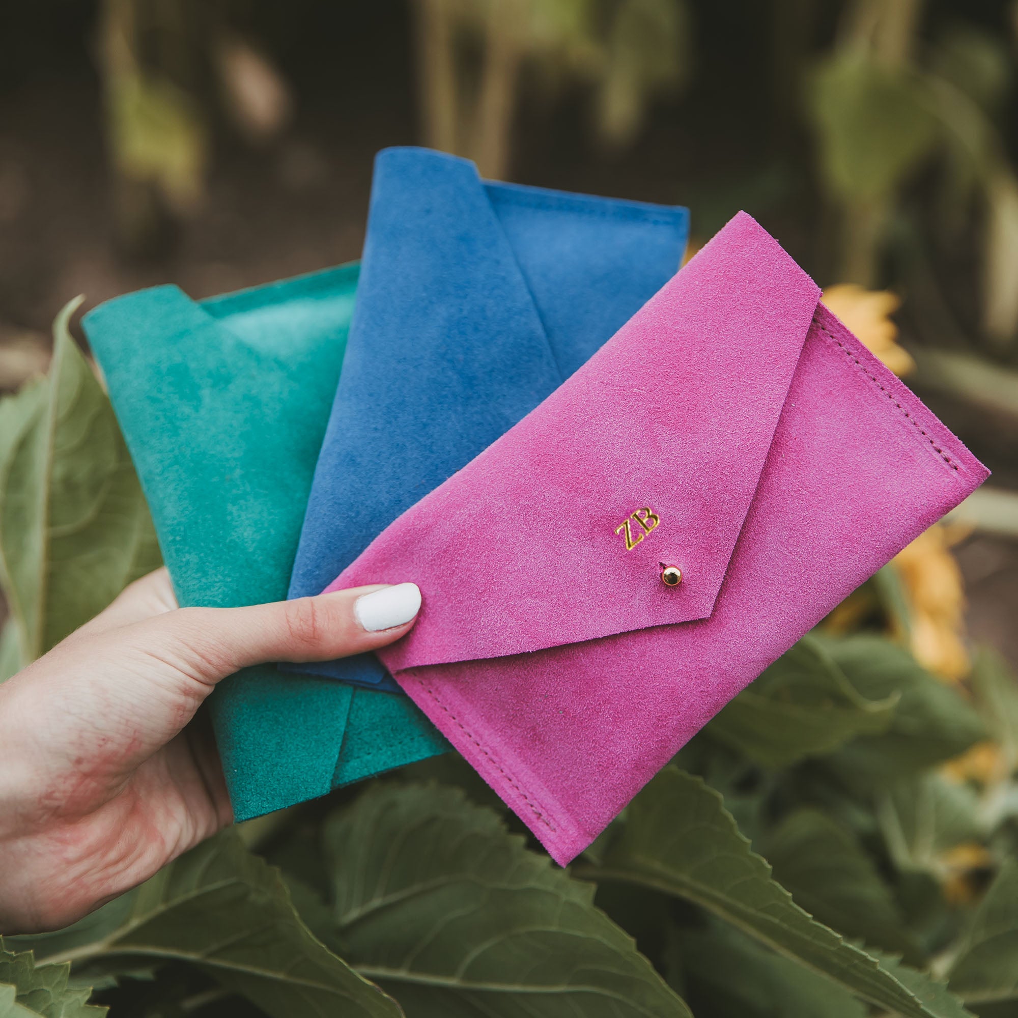 Green, Blue and Pink minimalist envelope style wallets on a blurred background.