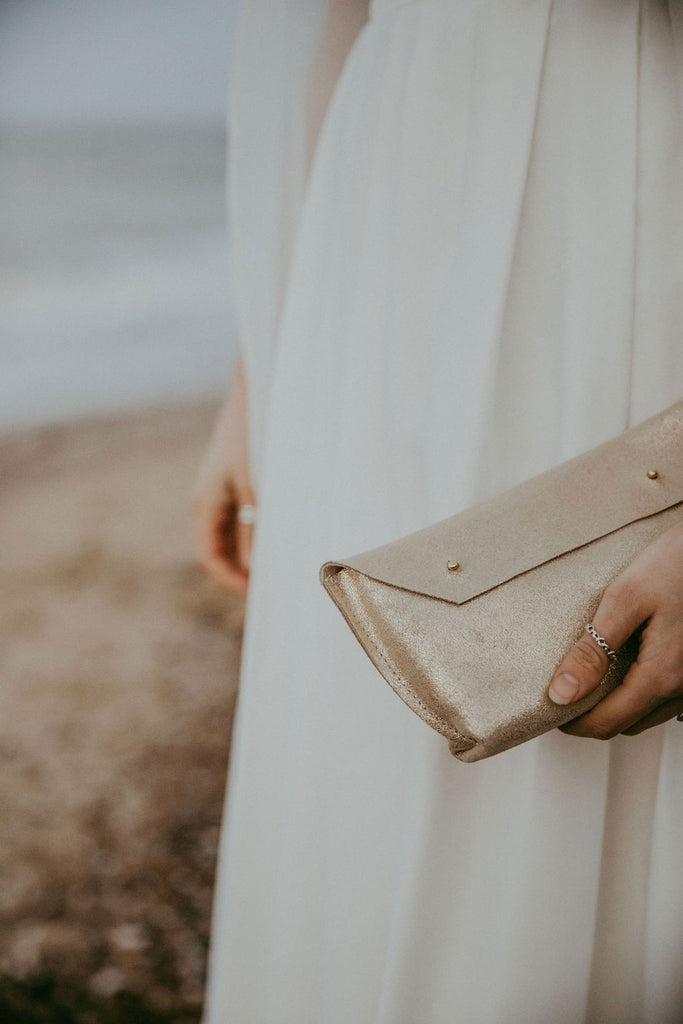 Bride holds gold glitter clutch bag on her wedding day.