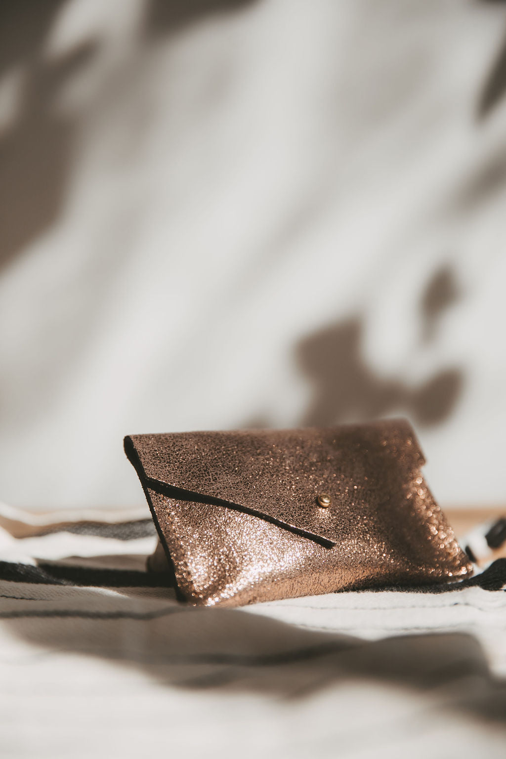 Bronze leather envelope wallet on a textured surface with soft lighting