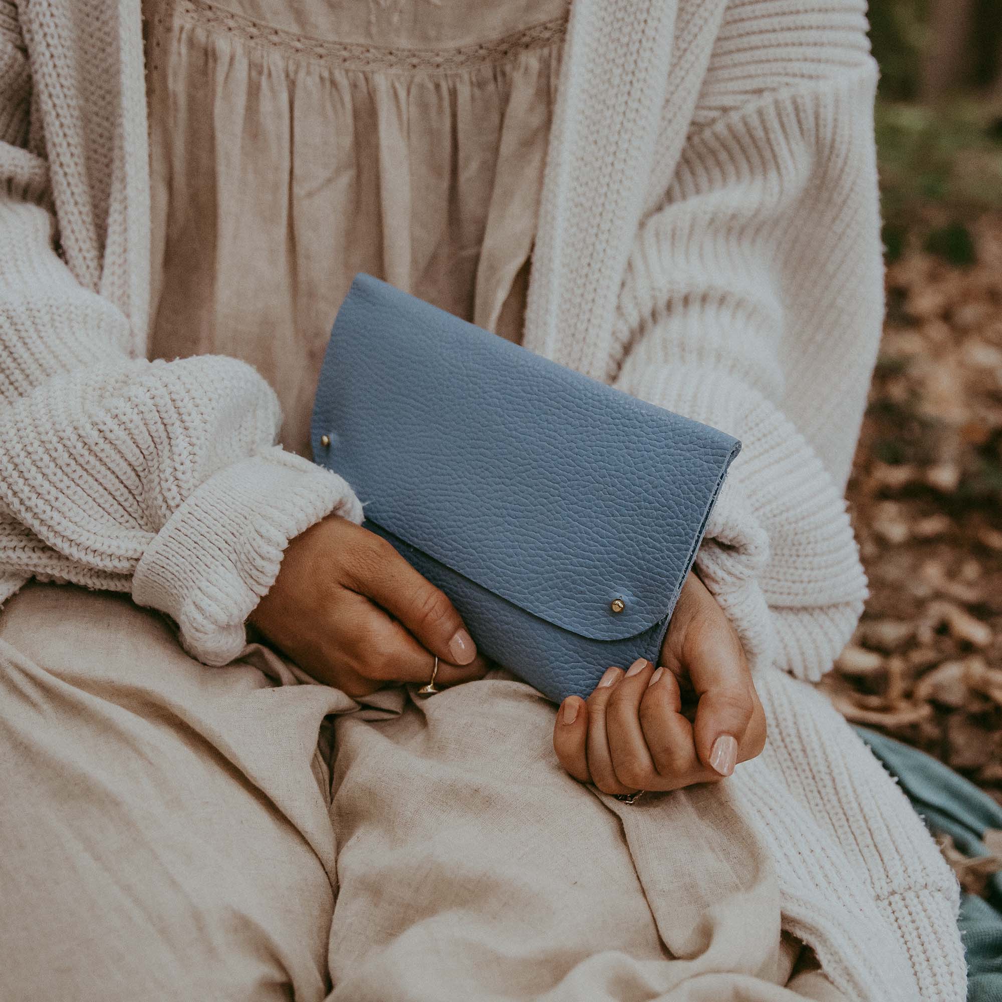 Woman holding the leather clutch bag in powder blue.