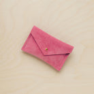 A suede Small Notions Pouch in Coral Pink. Complete with a stud for secure closing.