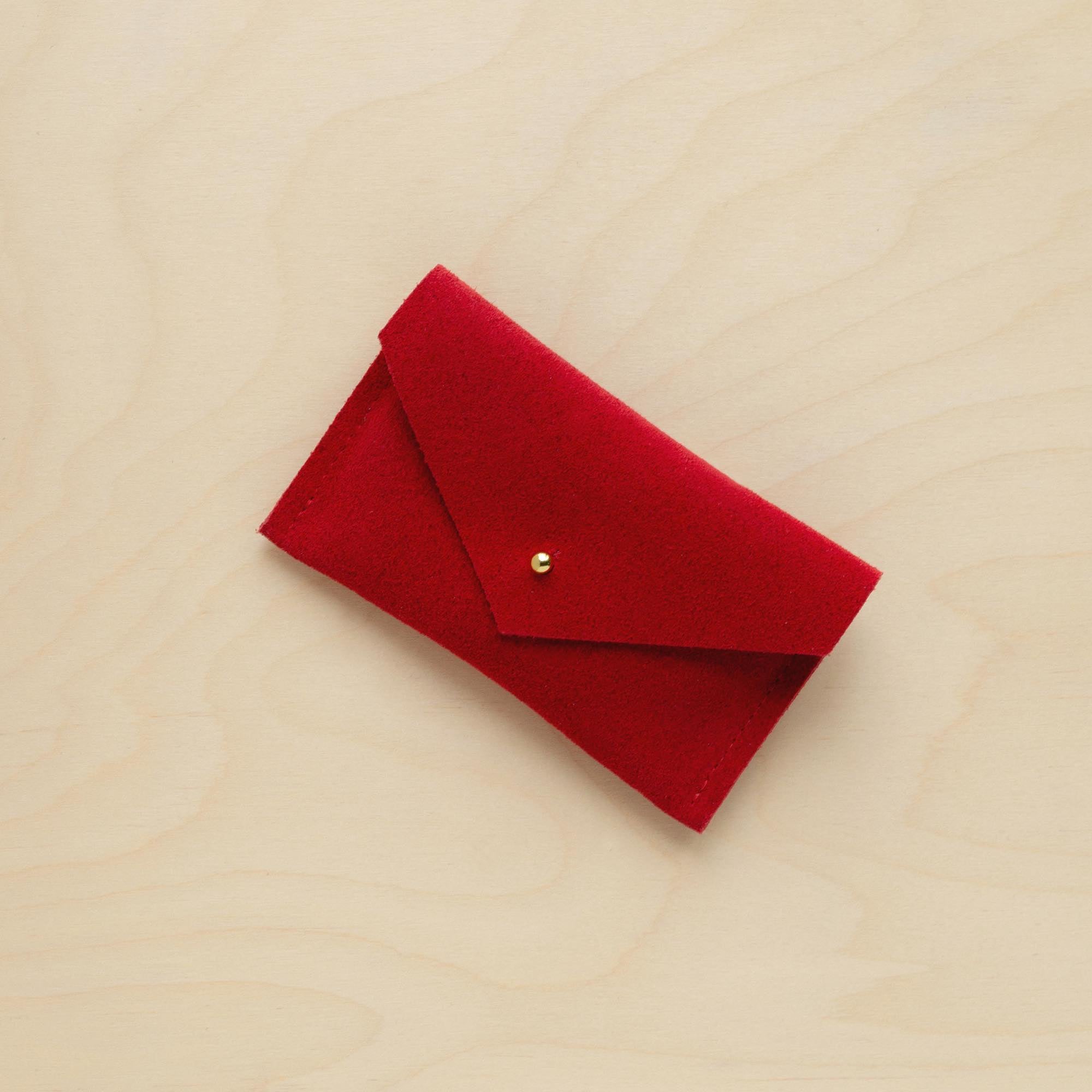 A suede Small Notions Pouch in Crimson Red. Complete with a stud for secure closing.