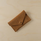 A suede Small Notions Pouch in Tan brown. Complete with a stud for secure closing.