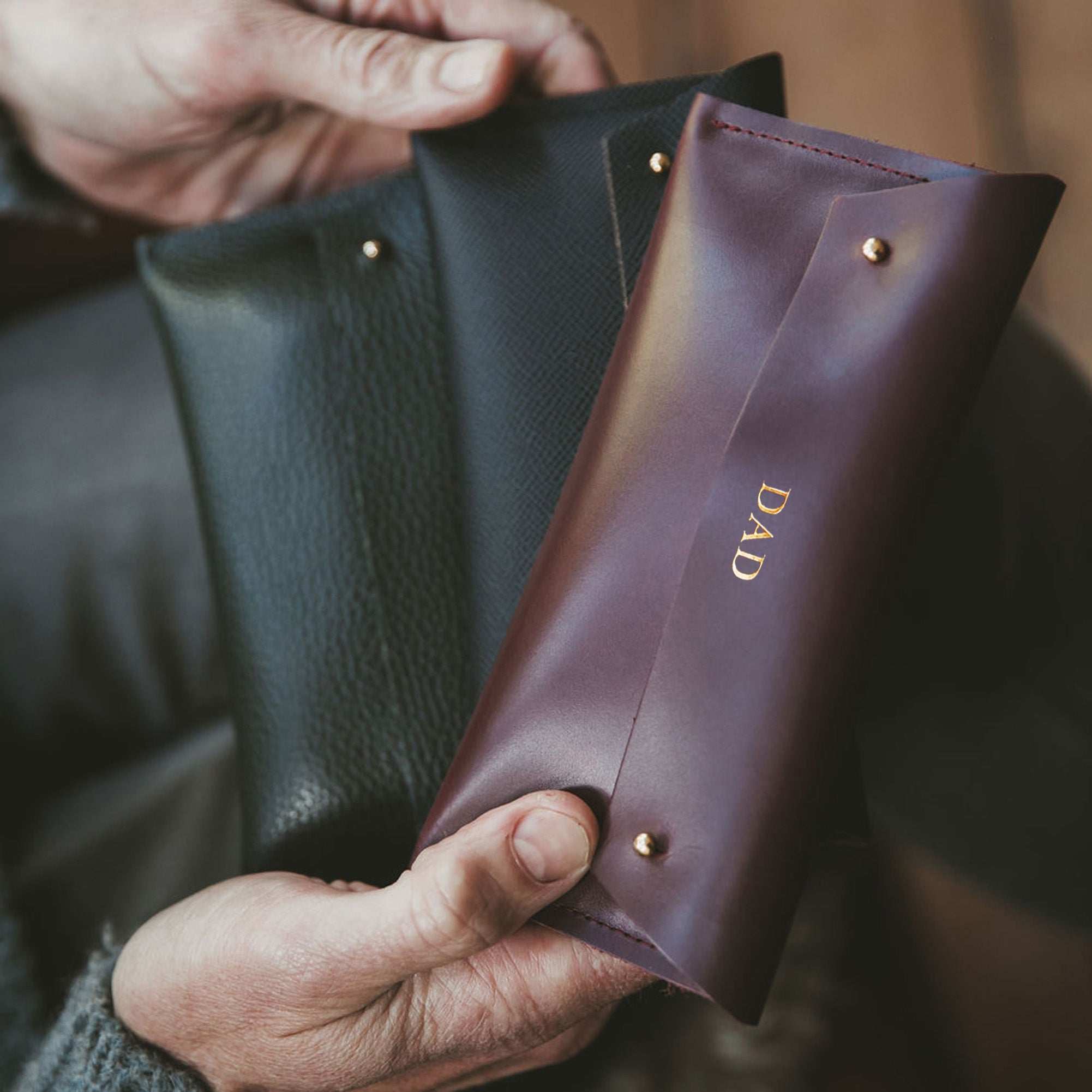 Man holds brown leather glasses case which is personalised with the word DAD.
