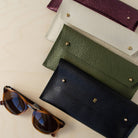 Four double stud glasses case in leather in black, olive green, cream and metallic berry.