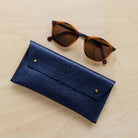 Metallic Navy leather double stud glasses case with sunglasses.