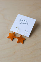 Star-shaped earrings on a card with 'Studio Lowen' text, placed on a wooden surface.