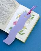 Purple wavy bookmark on an open book with floral illustrations on a blue background