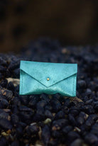 Turquoise leather envelope wallet on a textured black surface