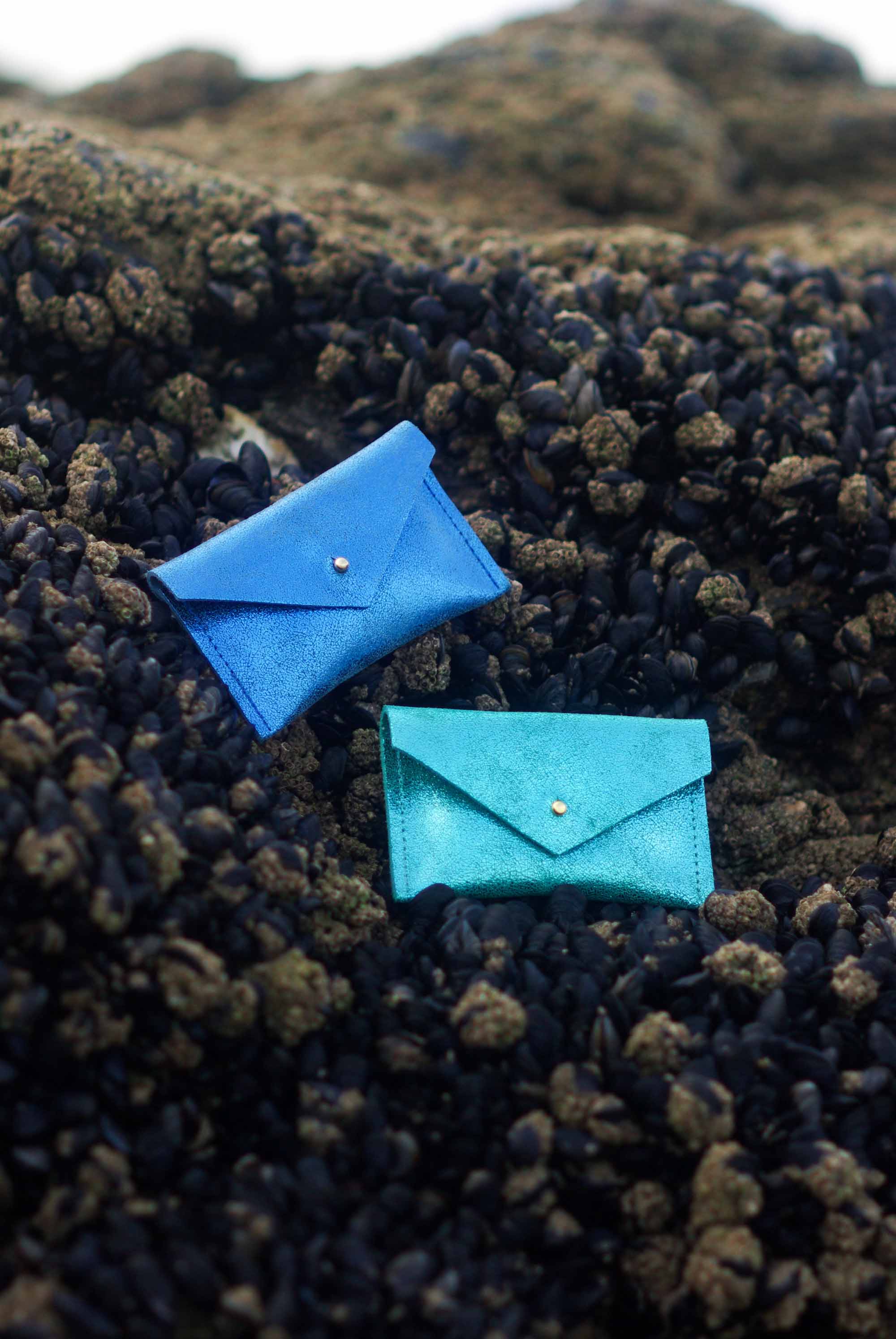 Two blue envelope leather wallets on a textured black surface
