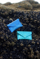 Two blue envelope leather wallets on a textured black surface