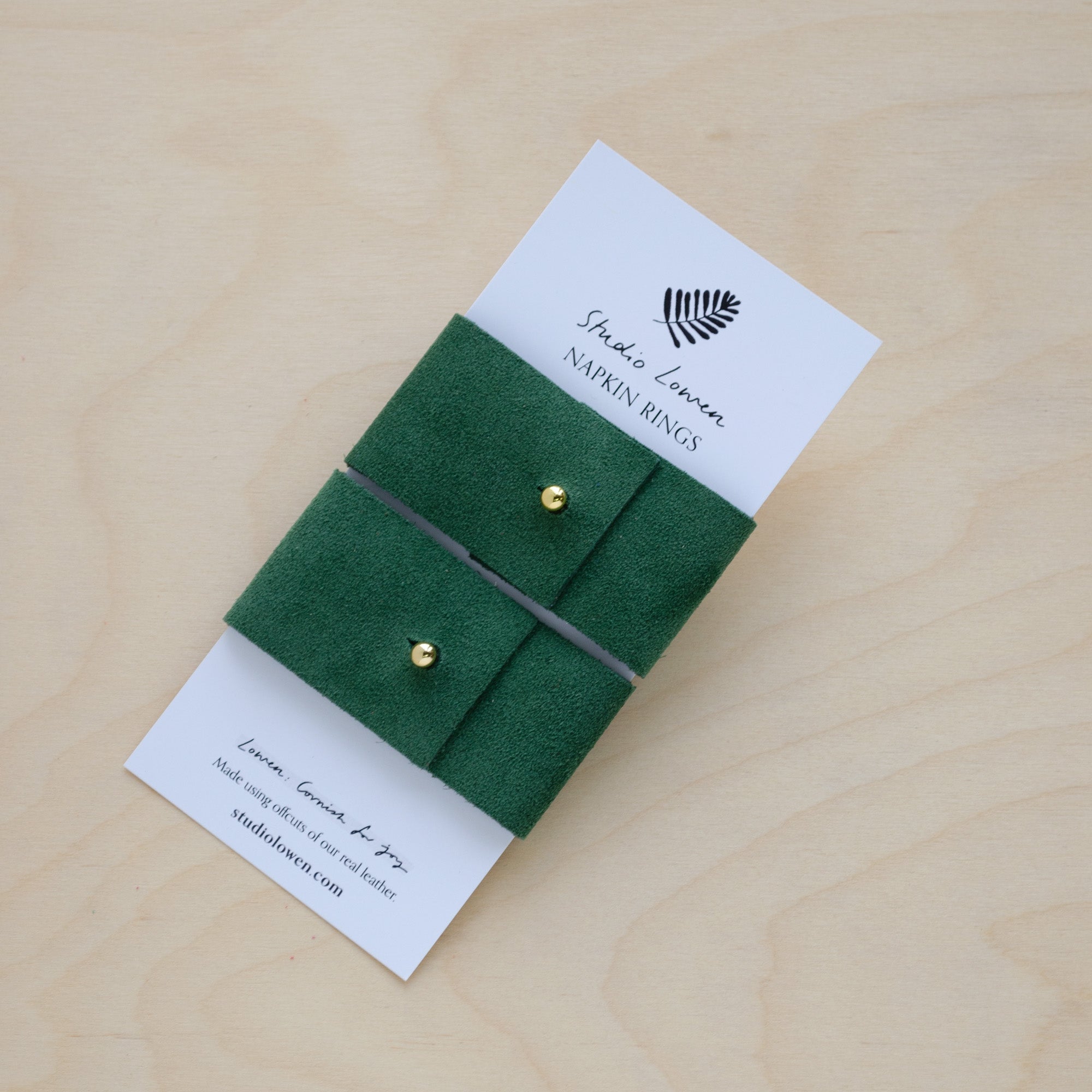 Pair of Moss Green suede napkin ring holders on a white card packaging.