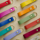 Colourful leather keyrings on a wooden background.