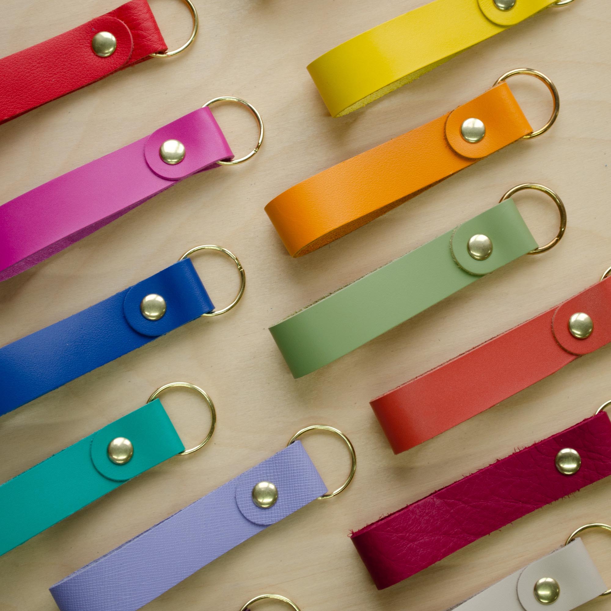 Colourful leather keyrings on a wooden background.