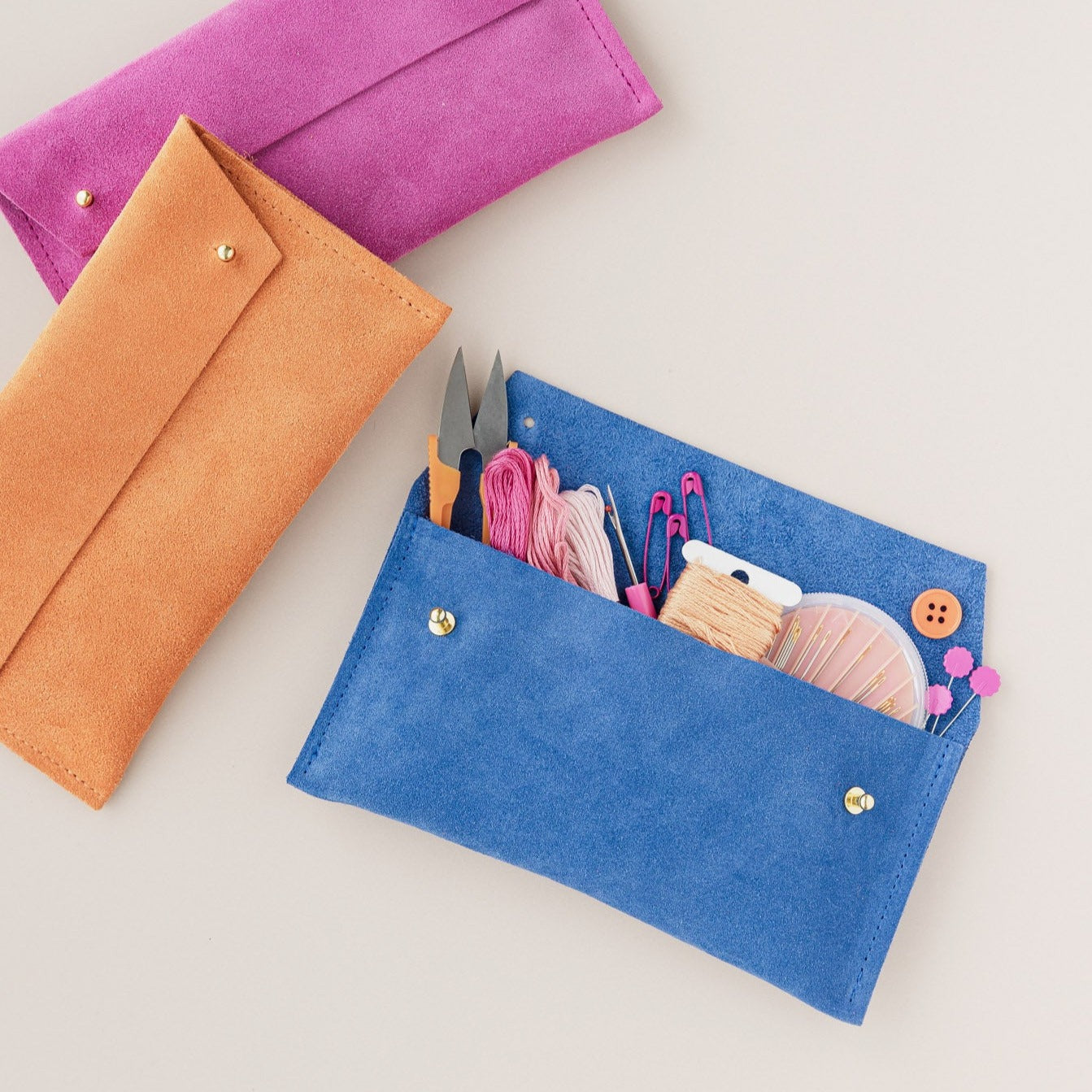 A selection of suede Notions Pouches in Fuchsia, Orange and Cobalt. Full with sewing notions. 