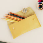 Open yellow leather pencil case with colourful pencils coming out and sharper.