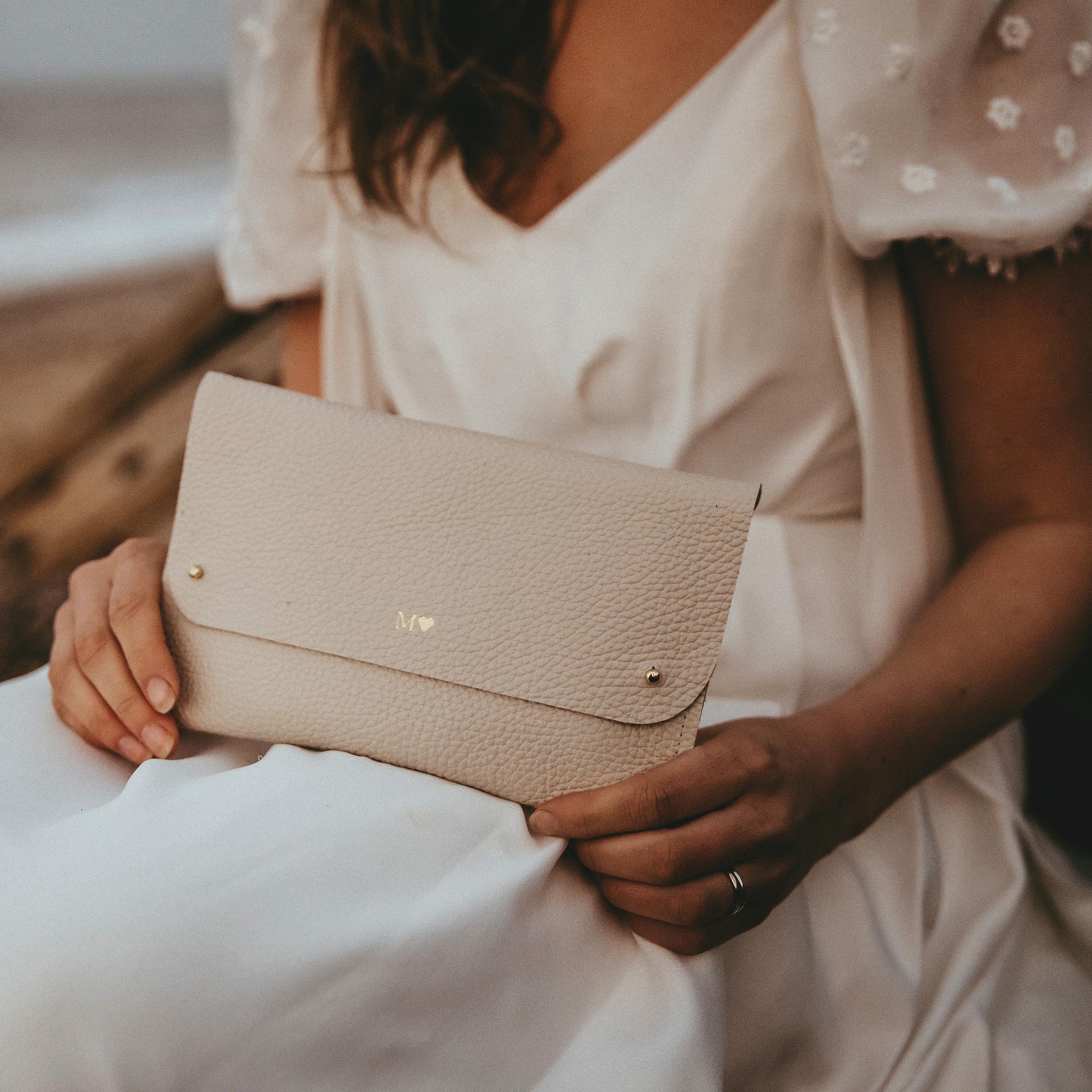 Bride holds her cream personalised cream leather clutch bag