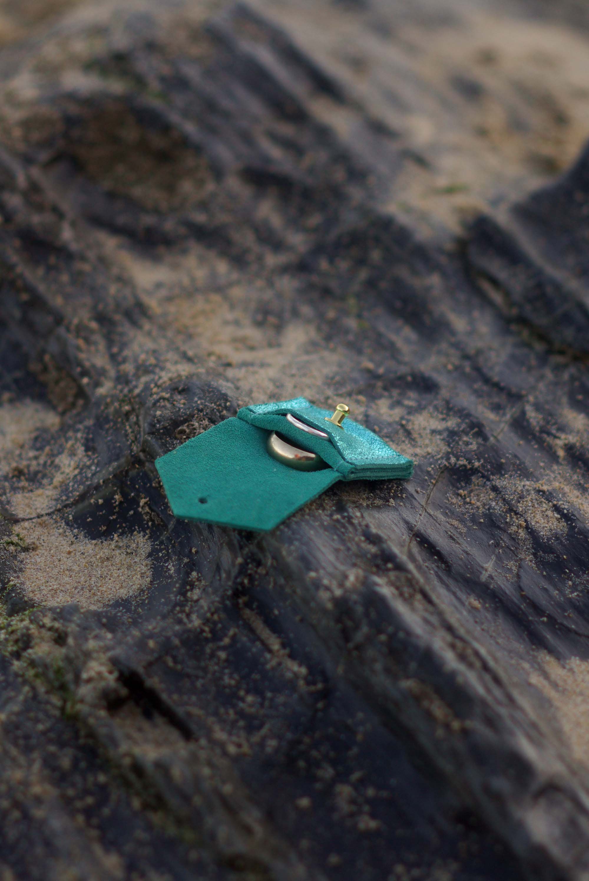 Turquoise leather wedding ring pouch with on a textured surface