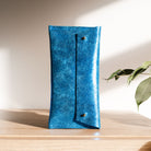 Metallic Royal Blue Glasses Case sits on a wooden table.