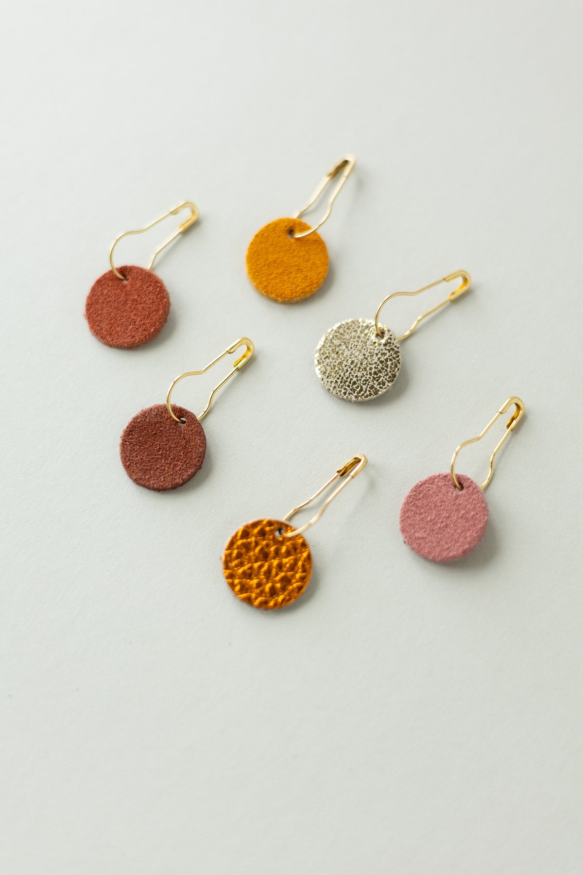 Colourful leather and suede stitch markers for knitting in oranges and browns.