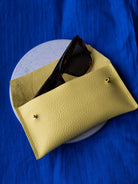 Yellow sunglasses case with sunglasses on a blue background