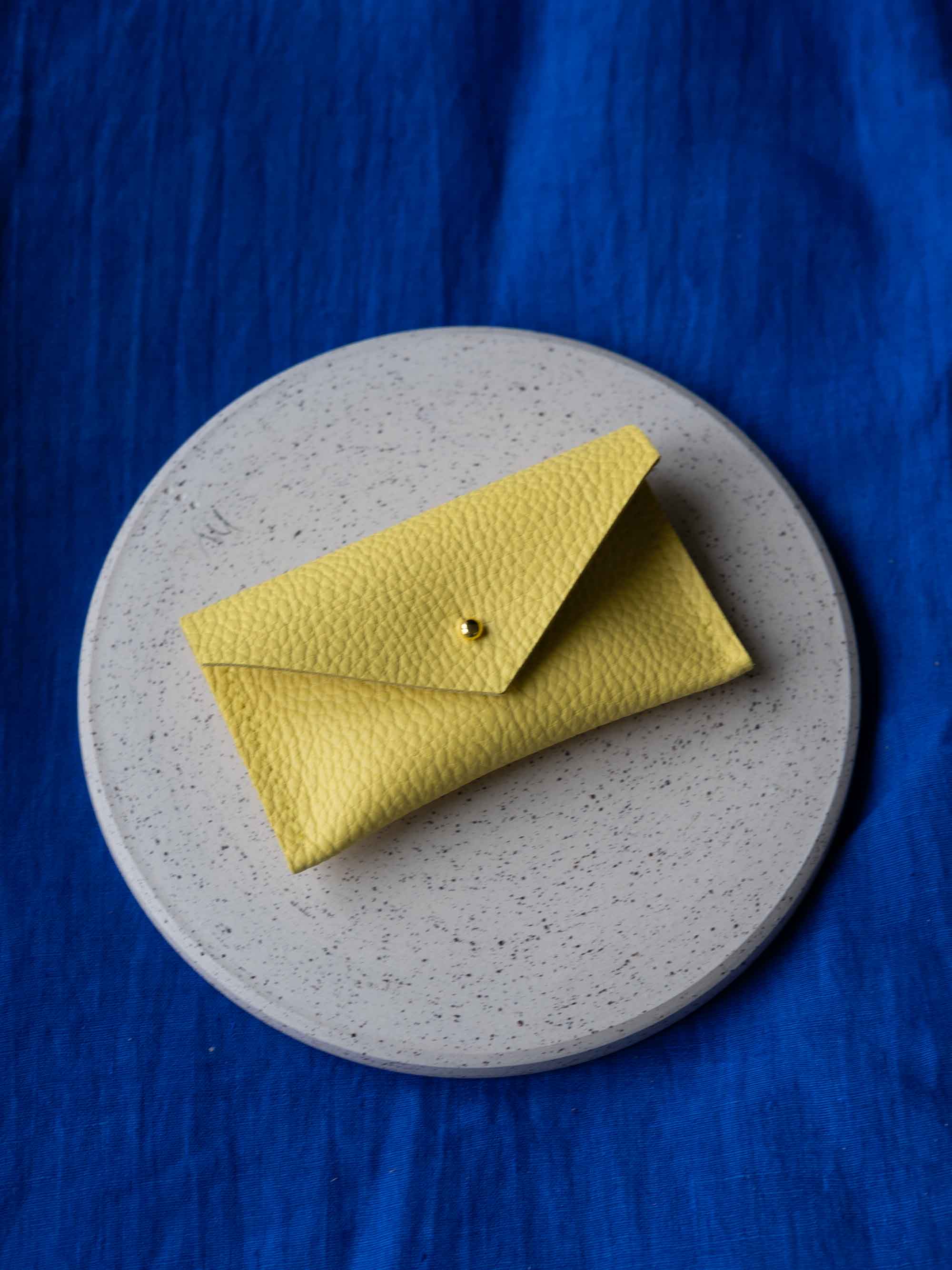 Yellow wallet on a gray plate with a blue background