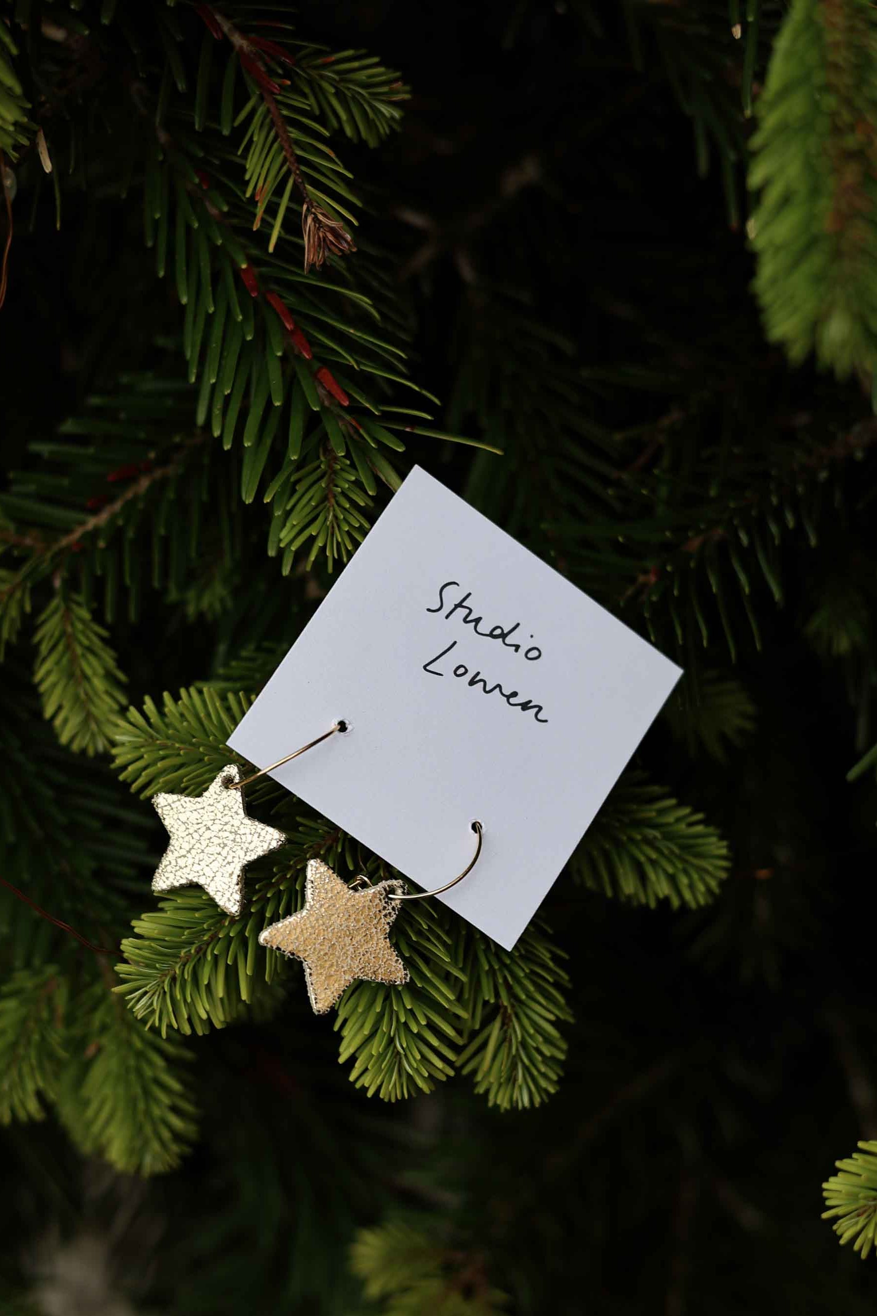 Gold star-shaped ornaments on a branch with 'Studio Lowen' label