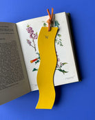 Yellow wavy bookmark with a letter 'W' on an open book against a blue background