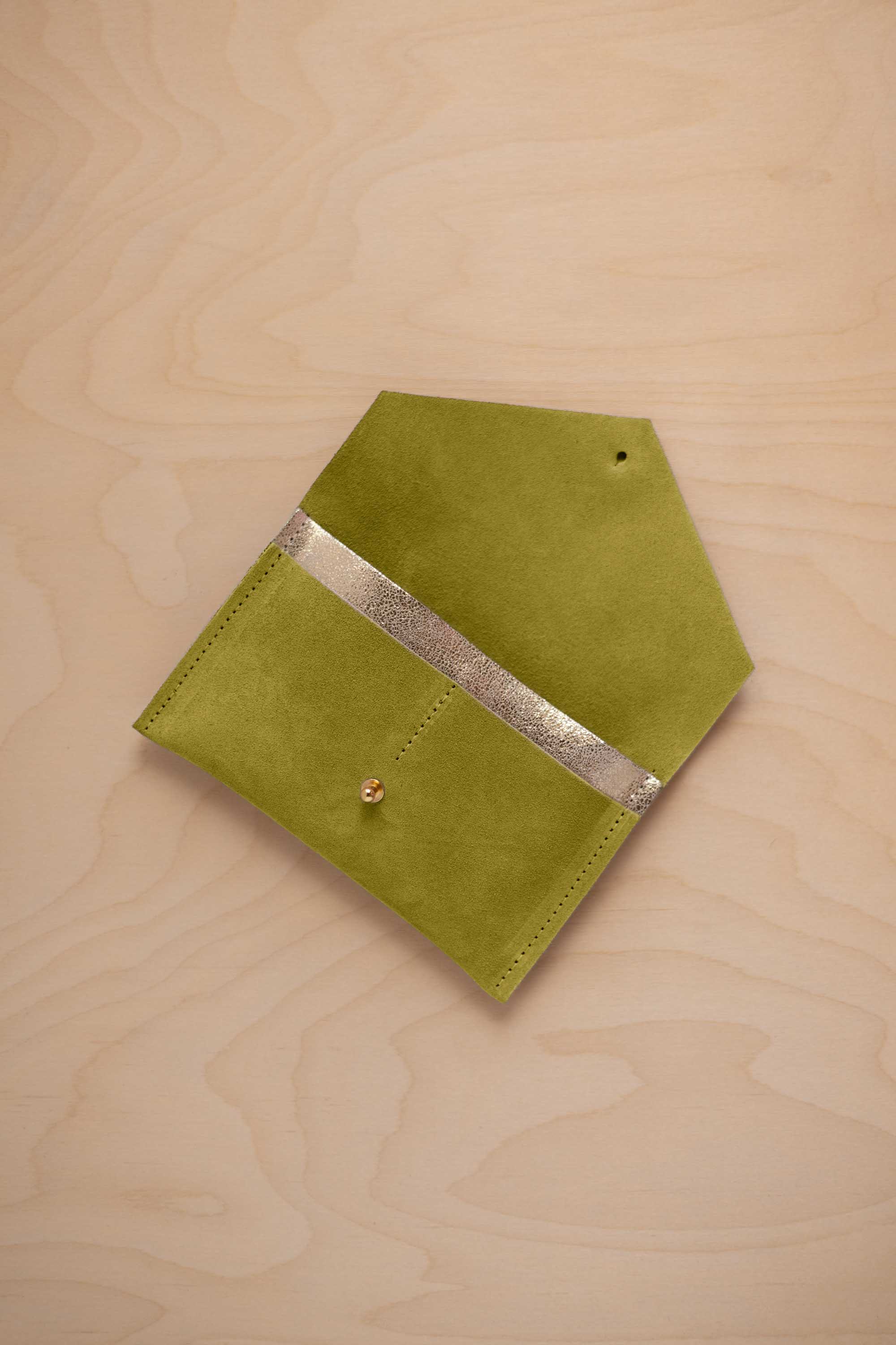 A chartreuse lime green coloured suede pouch with a metallic gold contrast pocket and a small gold stud, displayed on a light wood grain background.