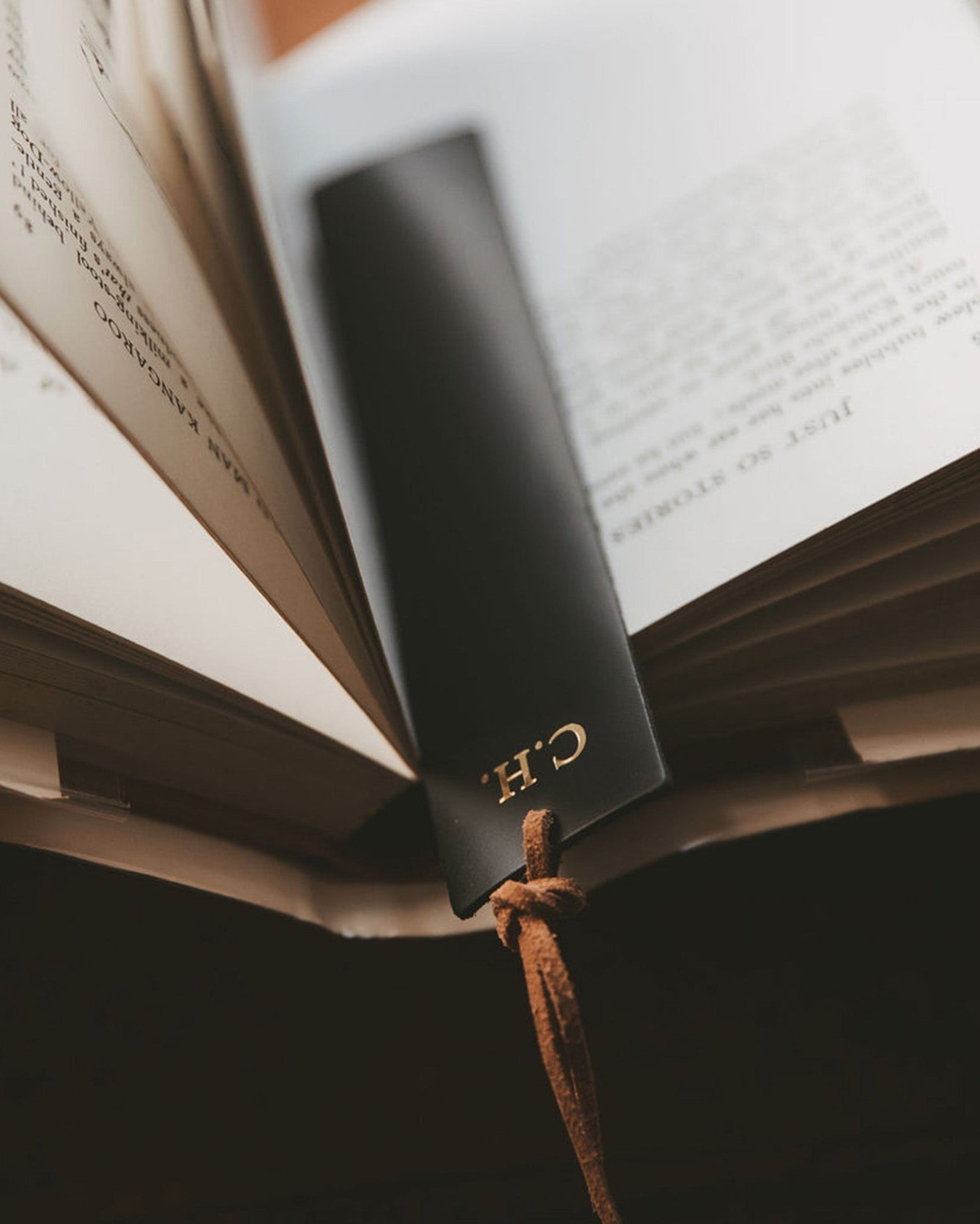Black leather bookmark with brown tassel and monogram "C.H." in gold.